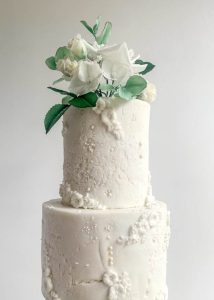 Textured iced wedding cake with bass relief detail and sugar flowers